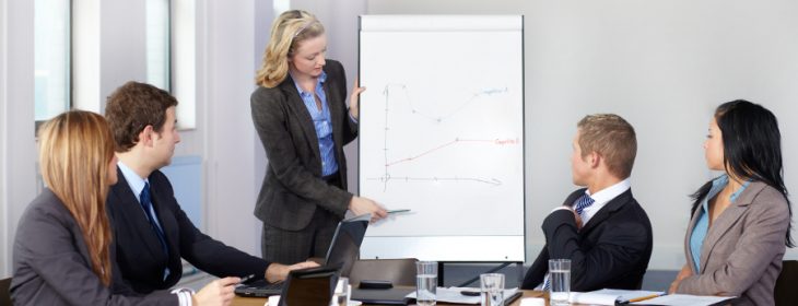 Blonde female present graph on flipchart during business meeting